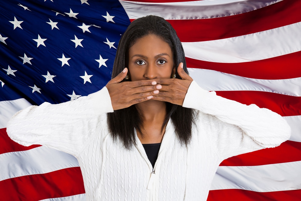 Free Speech - Women standing in front of US flag with hands over her mouth