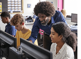 Black male teacher working with students in the computer lab.