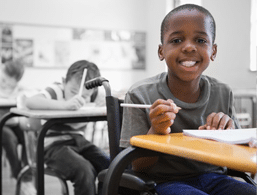 Disabled pupil smiling at camera in classroom