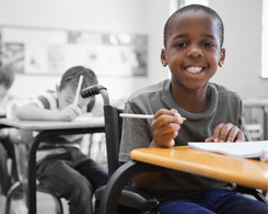 Disabled pupil smiling at camera in classroom