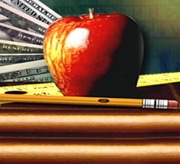 Stack of books and an apple in front of U.S. Currency