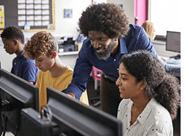 Black male teacher working with students in the computer lab.